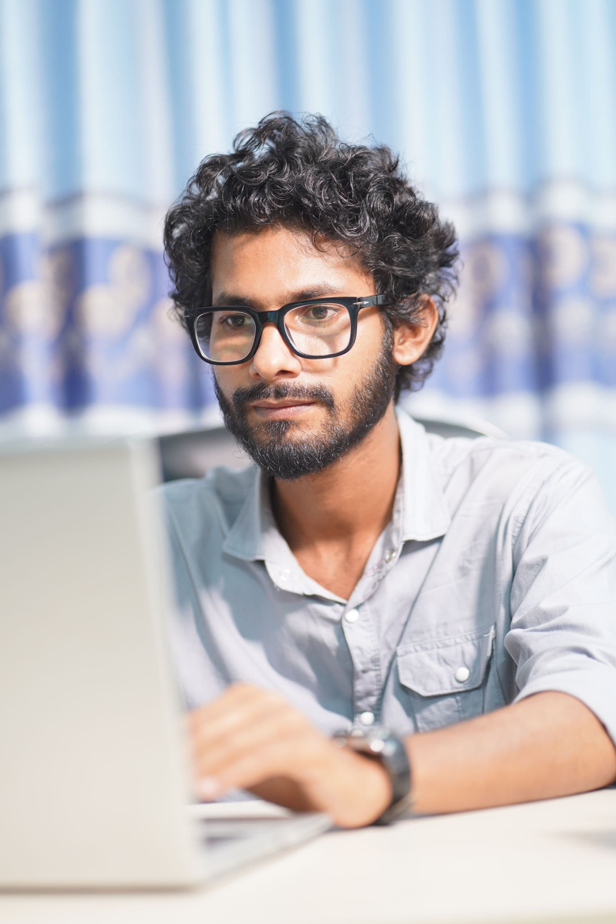 A developer concentrating on his laptop in a daylight workspace