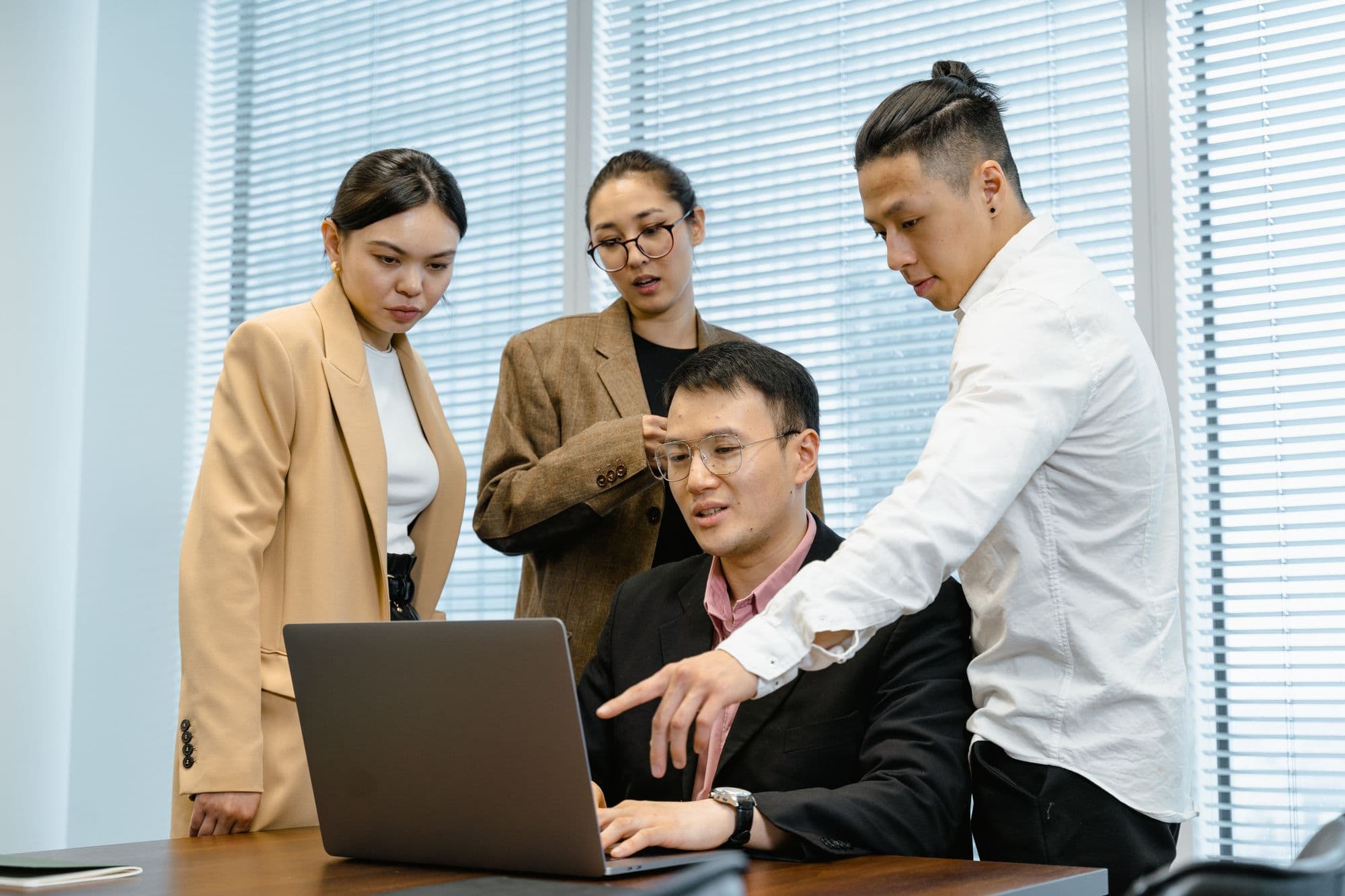 A team gathered around a laptop to discuss their work