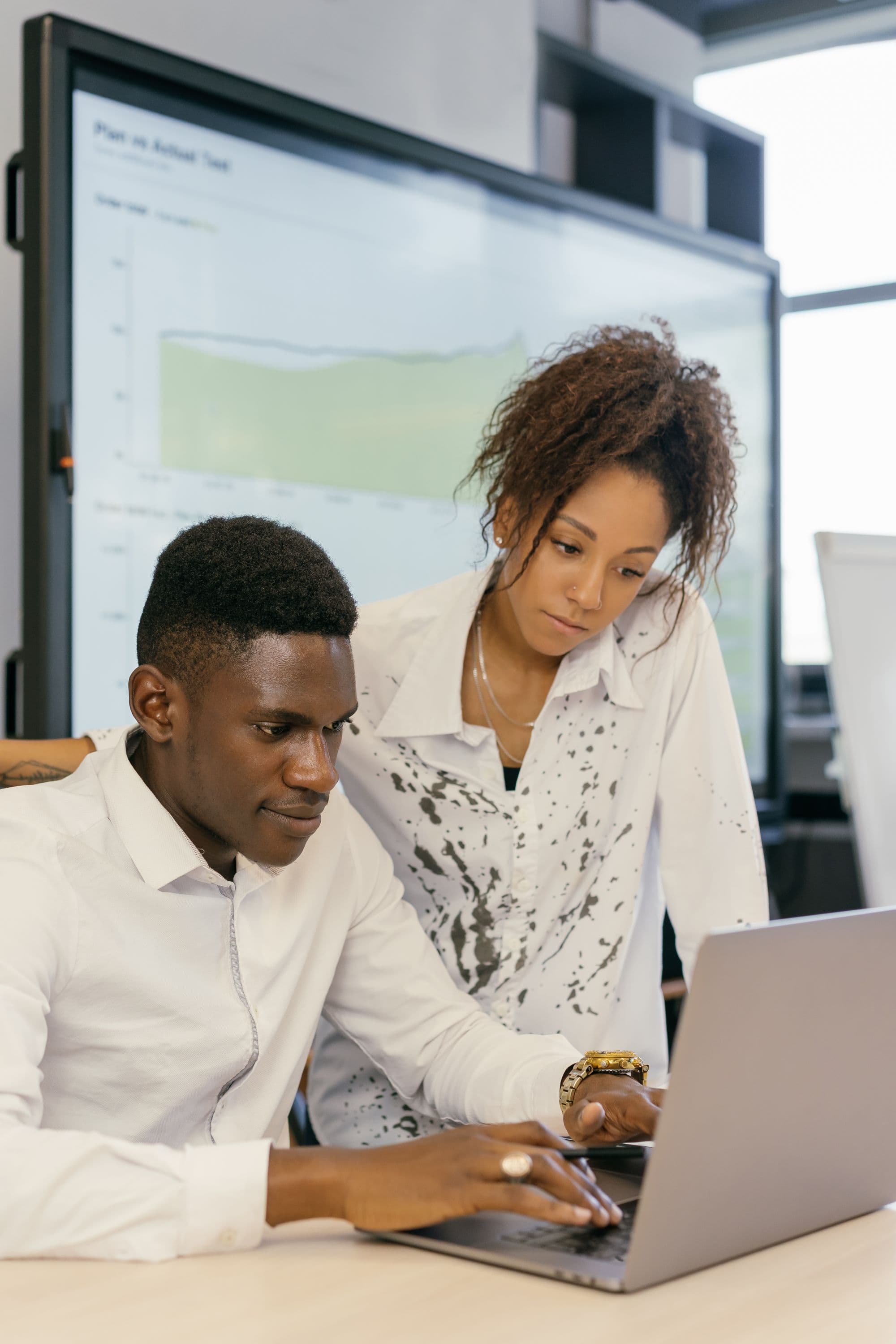 Two colleagues collaborating at a laptop in a modern office