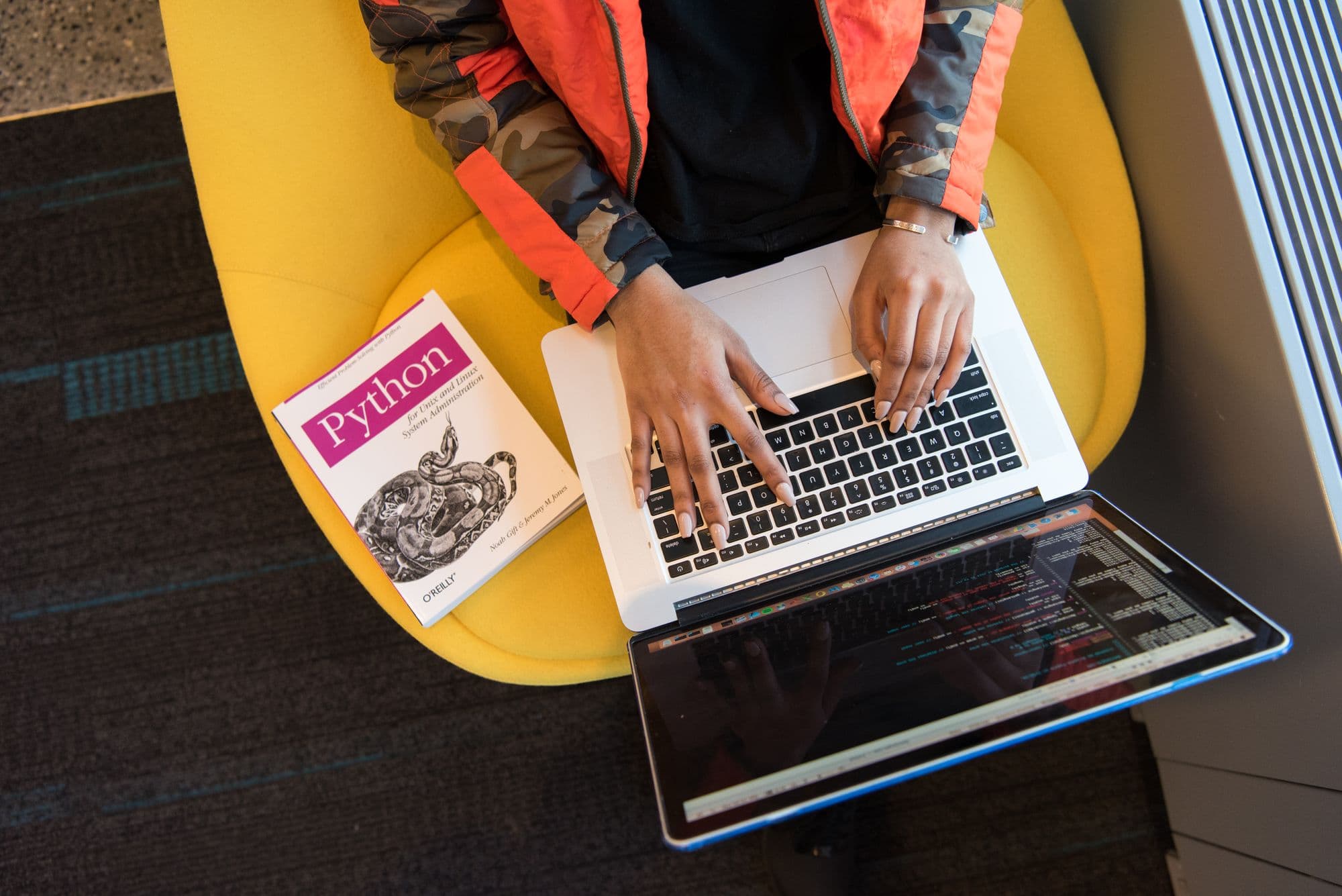A developer using a laptop while sitting in a yellow chair